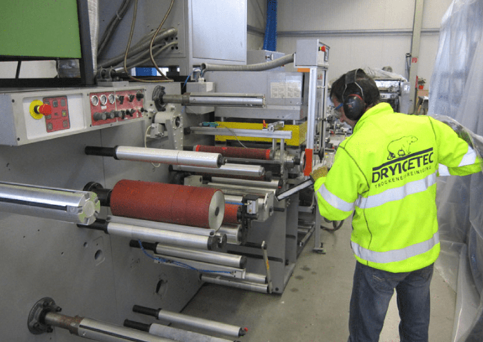 Bild einer Person in Schutzkleidung, die eine KLEMM Derby Druckmaschine bei ALS ENGINEERING GMBH reinigt.
